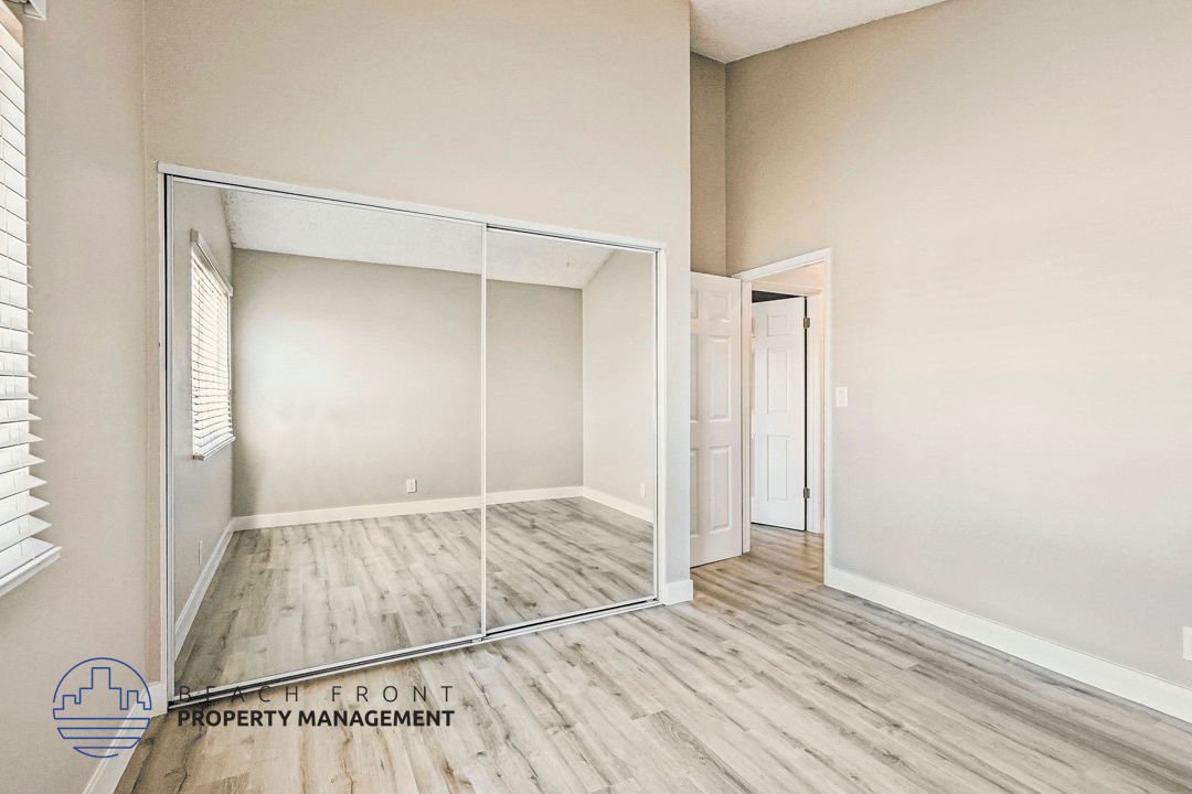 A room with a mirrored door and wooden flooring.